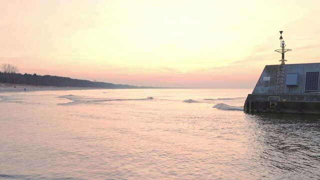 Soft sunset colors bathe the Baltic coast in Łazy by the breakwater and storm gate. 