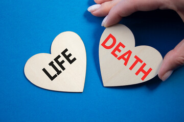 Life or Death symbol. Concept word Life or Death on wooden hearts. Businessman hand. Beautiful blue...