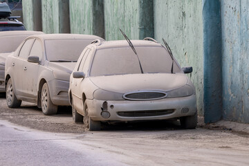 Dust covered cars parked on a city street with faded paintwork, highlighting neglect and urban...