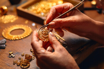 Artisan hands crafting fine gold jewelry using detailed tools in workshop