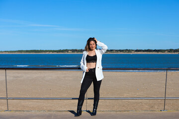 Young and beautiful blonde woman is leaning on the railing of the promenade at the mouth of the...