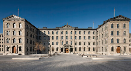 Fototapeta premium Historic Stone Building With American Flags Under Clear Blue Sky, Showcasing Architectural Heritage and Urban Revitalization