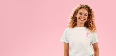 Smiling woman in white shirt with pink ribbon symbol for breast cancer awareness