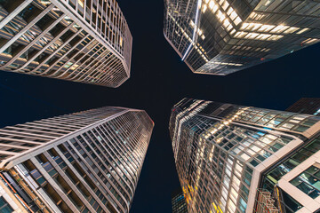 Looking up between the four illuminated skyscrapers at night