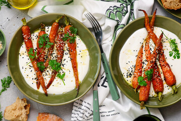 Baked baby carrots in honey glaze on whipped feta in a ceramic bowl . selective focus. hugge style