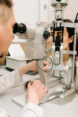 Ophthalmologist illuminates eye of patient with light from slit lamp to diagnose the eyes and...