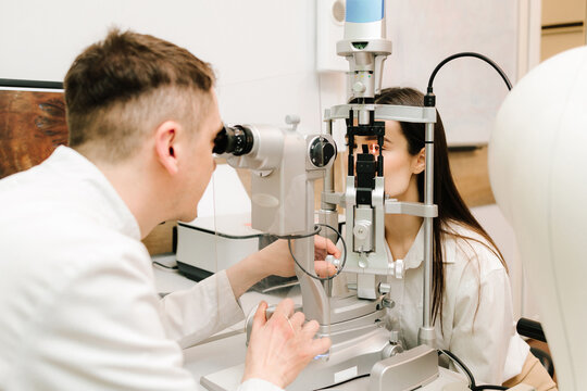 Slit lamp eye and cornea diagnostic at visiting ophthalmology clinic. Light on eye from slit lamp for examination eyes and cornea of girl.