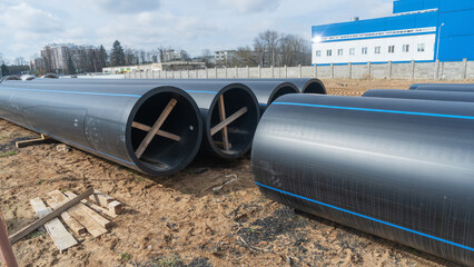 Construction site featuring various diameters of polyethylene pipes for water supply. Durable and...