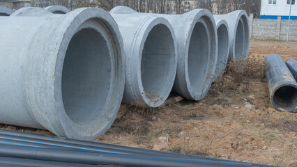 Construction site showcasing various diameters of polyethylene and concrete pipes for water supply....
