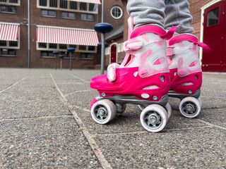 A child’s feet, poised and ready in vibrant pink roller skates, symbolize the joy of active living and the thrill of learning a new sport.