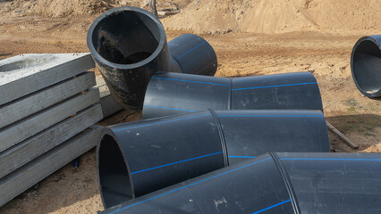 Construction site featuring various diameters of polyethylene pipes for water supply. Durable and...