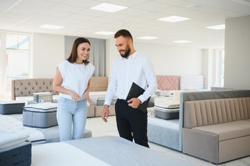 A young salesman consults a female customer in a furniture store
