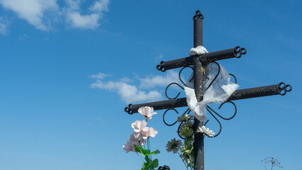 A cross stands against the sky at a cemetery, symbolizing faith, hope, and resurrection....