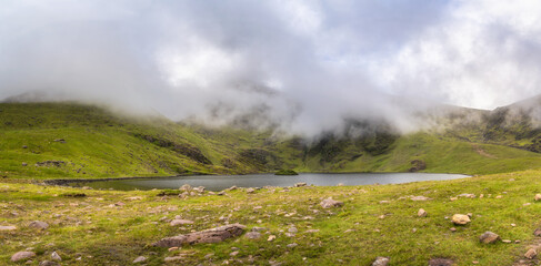 A breathtakingly stunning view of a tranquil lake nestled amid lush, verdant hills, with soft, misty clouds floating above, showcasing the remarkable beauty of nature, Kerry, Ireland