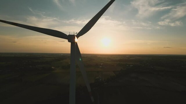 Aerial drone shot of a wind turbine at sunset, symbolizing clean and renewable energy in harmony with nature