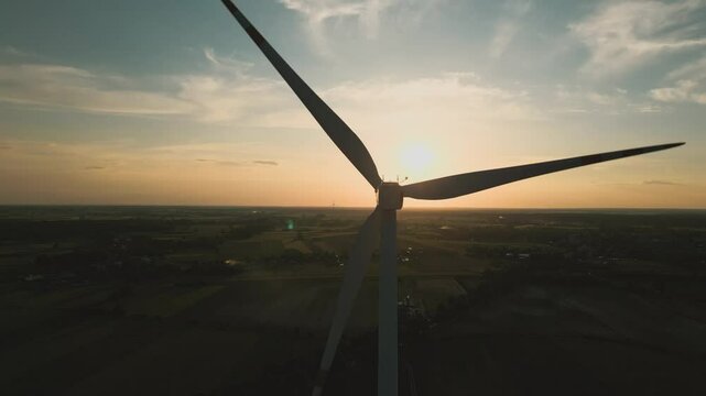 Aerial drone shot of a wind turbine at sunset, symbolizing clean and renewable energy in harmony with nature