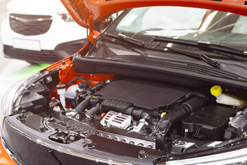 Open hood of a new car revealing engine in auto shop