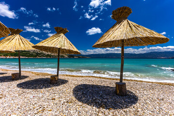 Sunshades on the beach of Baska on the island of KRK, preparation for the tourist season in Croatia