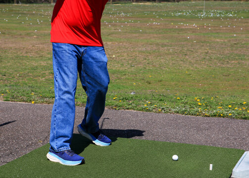 Golfer Preparing to Swing at Driving Range on a Sunny Day - Powered by Adobe