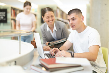 Female student talking to male student near laptop, they are preparing for exams and diploma