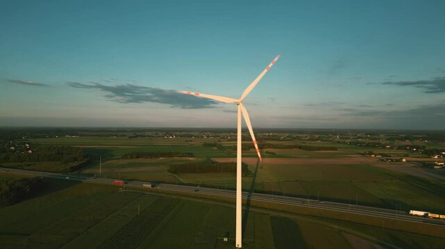Aerial drone shot of a wind turbine at sunset, symbolizing clean and renewable energy in harmony with nature