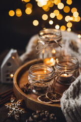 Creative handmade christmas home decor decorations: simple glass jars with aroma candles decorated with a ribbon, cinnamon, anise, dry orange. Cozy atmospheric composition for holiday mood creation