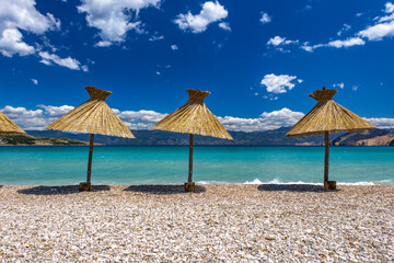 Sunshades on the beach of Baska on the island of KRK, preparation for the tourist season in Croatia