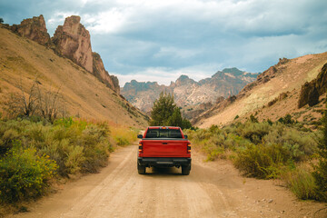 Red truck is off-roading through Succor Creek State Natural Area in Owyhee Canyon near Leslie Gulch in Oregon, USA