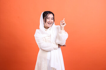 Enthusiastic muslim woman pointing upwards, conveying inspiratio