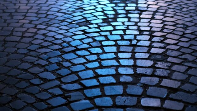 Wet cobblestone street reflecting blue light at night. Blue-tinted nighttime wet cobblestone street gleaming with reflective surfaces, casting enigmatic urban landscape