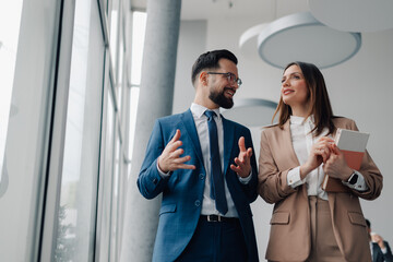 Businesspeople discussing work while walking in office hallway