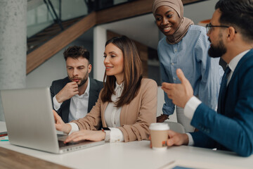 Business team collaborating on laptop in modern office