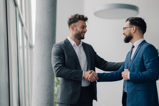 Two businessmen shaking hands in modern office building