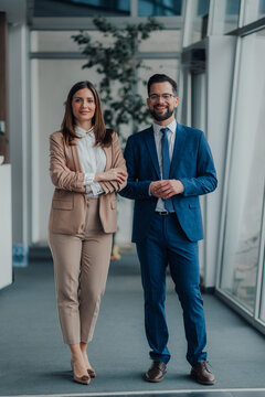 Portrait of two business people smiling in modern office hallway