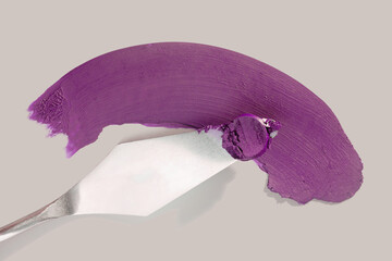 Cosmetic make up product sample swatch. Vine purple colored lipstick with spatula on beige...