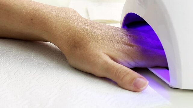 Process of manicure with led lamp. Hand in drying machine