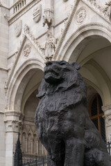 Bronze statue of a lion in front of the beautiful ancient building of the Hungarian Parliament in neo-gothic style