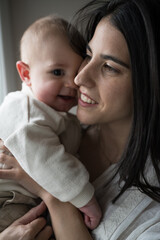 Mother holding her smiling baby, showing love and tenderness