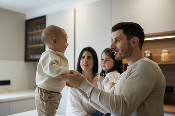 Fototapeta premium Happy family interacting with baby in modern kitchen