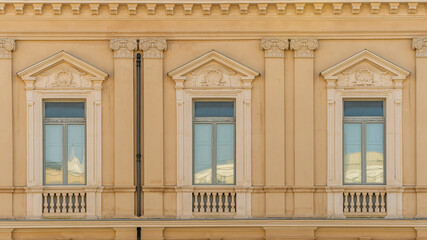 old yellow facade of house with three brown vintage wooden windows in retro italian european style