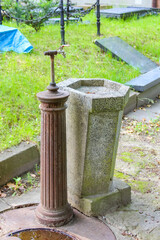 Fototapeta premium Stone water well with vintage hand pump showing traditional cemetery utility infrastructure and historic craftsmanship