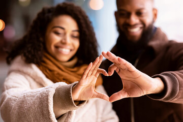 Romantic Relationship Concept. Portrait of happy smiling black african american couple making heart shape with hands walking together in the evening, selective focus. Love, Connection And Bonding