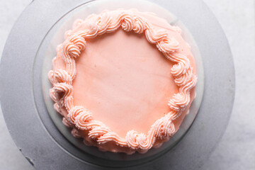 piping border on Pink buttercream cake on a cake plate, Cake covered in pink frosting, process of decorating a cake with pink buttercream