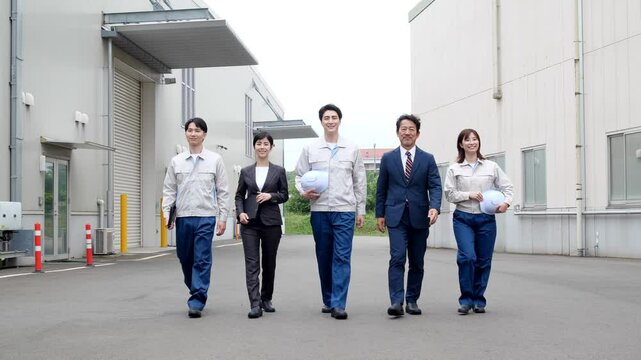 工場の前を歩く作業員グループ