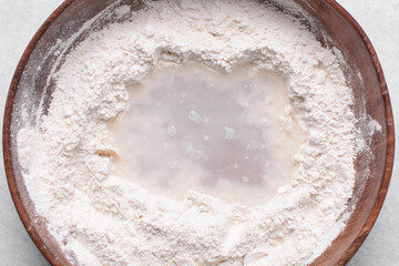 Overhead view of paratha dough being mixed in a wooden bowl, top view of flaky flatbread dough in a wood bowl, process of making paratha