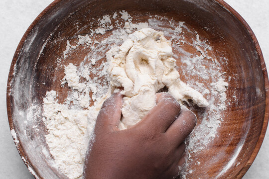 Overhead view of paratha dough being mixed in a wooden bowl, top view of flaky flatbread dough in a wood bowl, process of making paratha