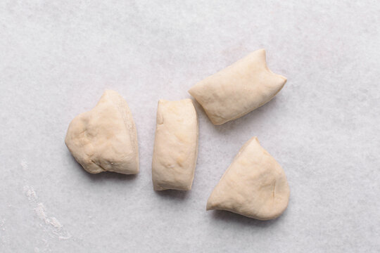 Overhead view of paratha dough on white marble countertop, top view of flaky flatbread dough on white background, process of making paratha