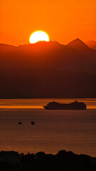 Golden sunset over calm sea with a passenger cruise ship on the horizon, warm evening light reflecting on the water, serene travel and vacation scene