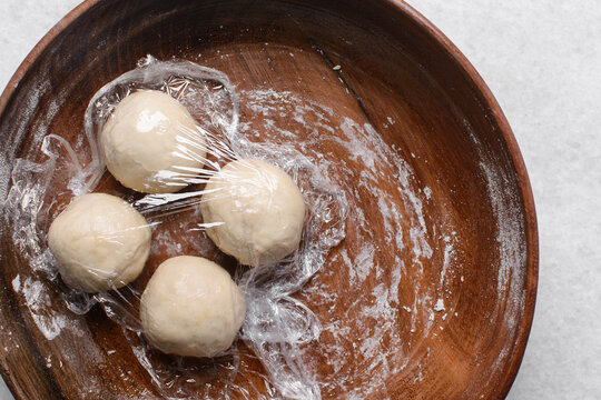 Overhead view of paratha dough in a wooden bowl, top view of flaky flatbread dough in wood bowl, process of making paratha