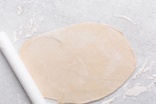 Overhead view of paratha dough being rolled out, top view of flaky flatbread dough, process of making paratha	